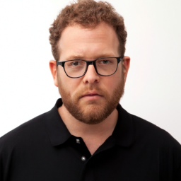 description: a photo of seth rogen in a black shirt with a white background, looking straight at the camera with a serious expression.