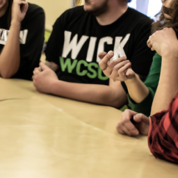 description: an anonymous image depicting a group of people discussing the potential legalization of marijuana in wisconsin. they are engaged in a conversation, gesturing and expressing different opinions.