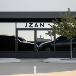 Description: An image of a storefront with a sign that reads "Zen Leaf" in front of a parking lot with several cars parked. The storefront has a modern design with large glass windows and a clean, minimalist aesthetic.